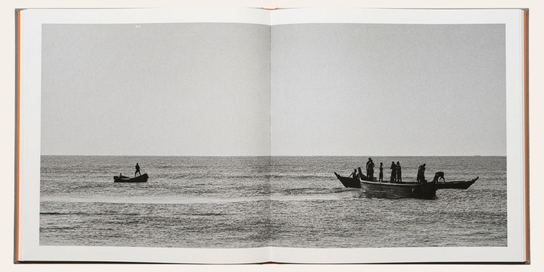 The Matriarch's Line opened flat to spread 049 — a wide black-and-white photograph of two wooden fishing boats on the sea: a lone paddler standing tall in a small boat on the left, and a crew of standing figures in a larger boat on the right, silhouetted against a hazy horizon.